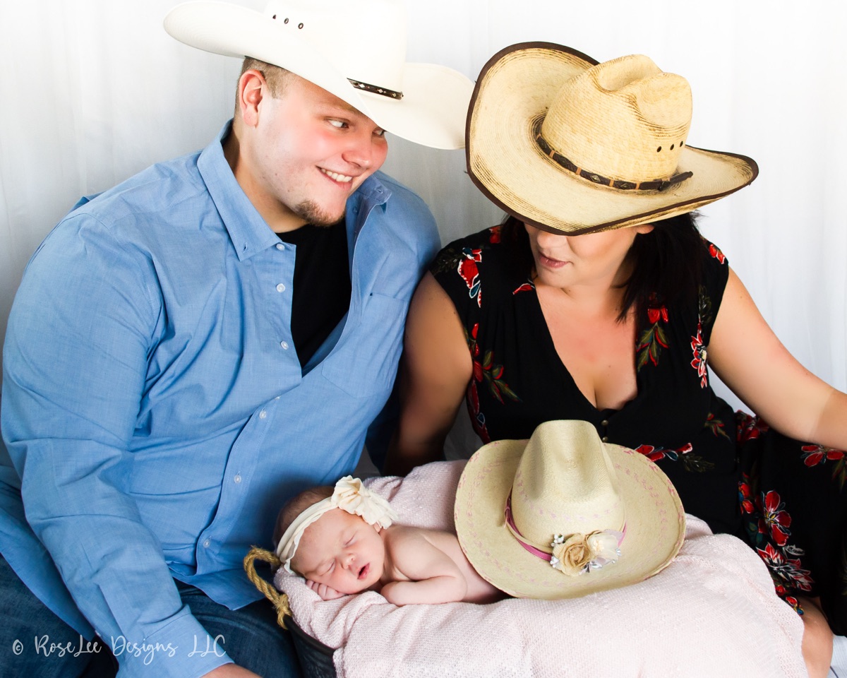 Parents in cowboy hats with their sleeping newborn