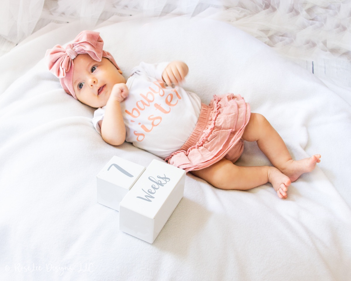 Baby in pink beside small milestone blocks