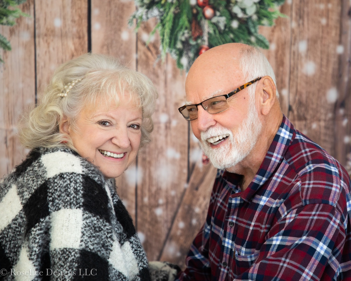 Older couple laughing together in a festive Christmas portrait