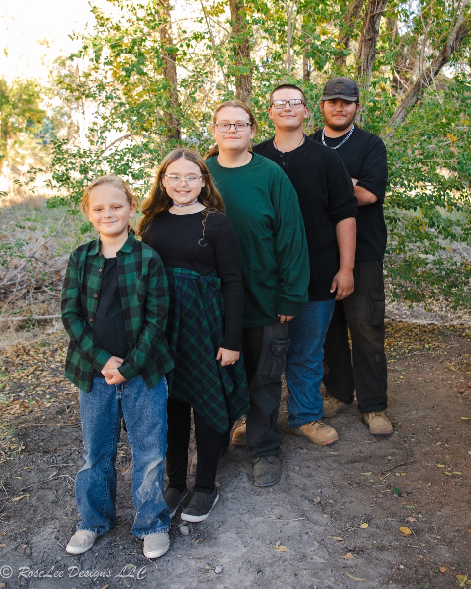 Family standing together beneath trees on a wooded path