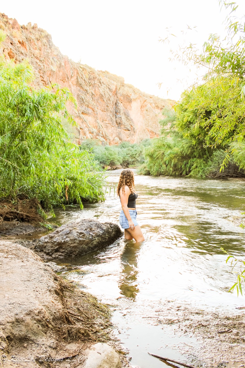 Young woman standing beside a river beneath canyon walls