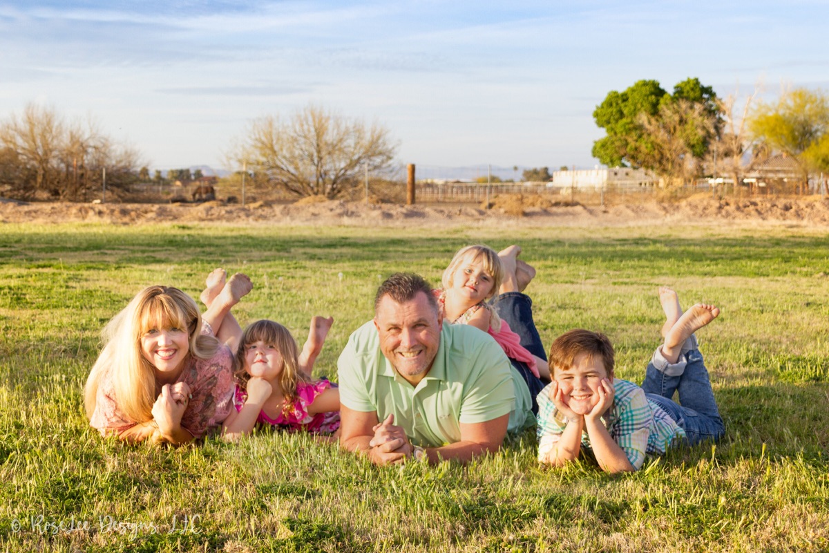 Family lying together and laughing in a sunlit field