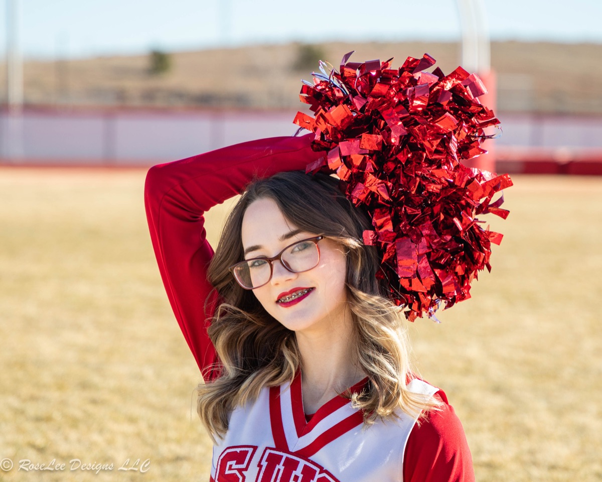Cheerleader holding a red pom-pom above her head