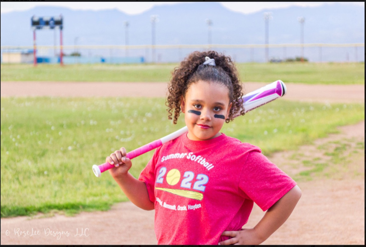 Young softball player with a pink bat resting on her shoulder