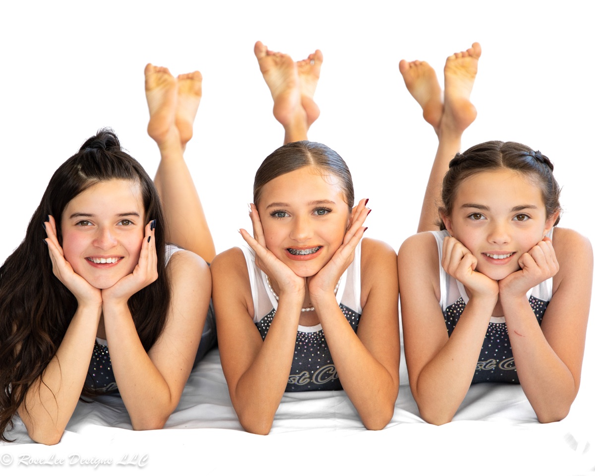 Three smiling gymnasts lying together in a studio portrait