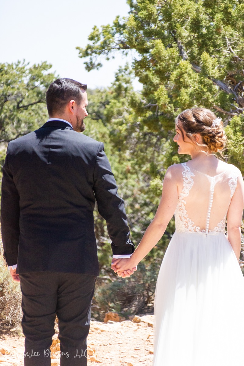 Newlyweds walking hand in hand along a sunlit wooded path