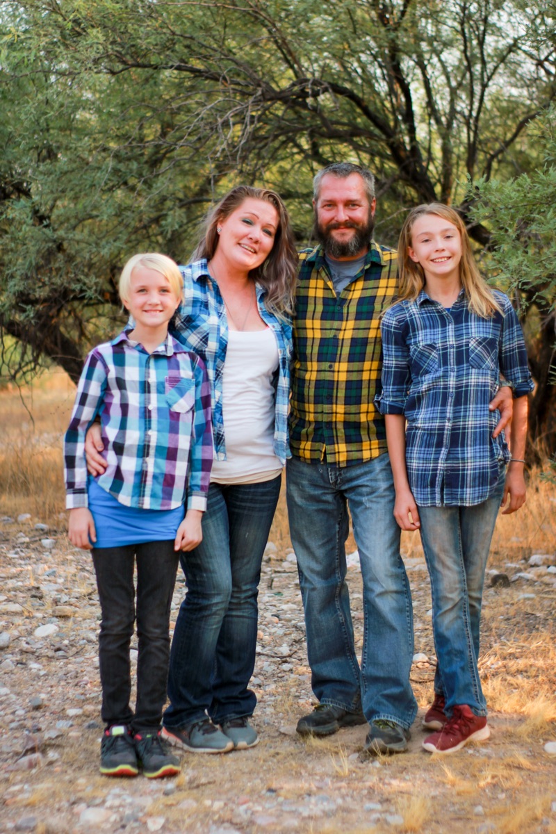 Family standing close together on a wooded path