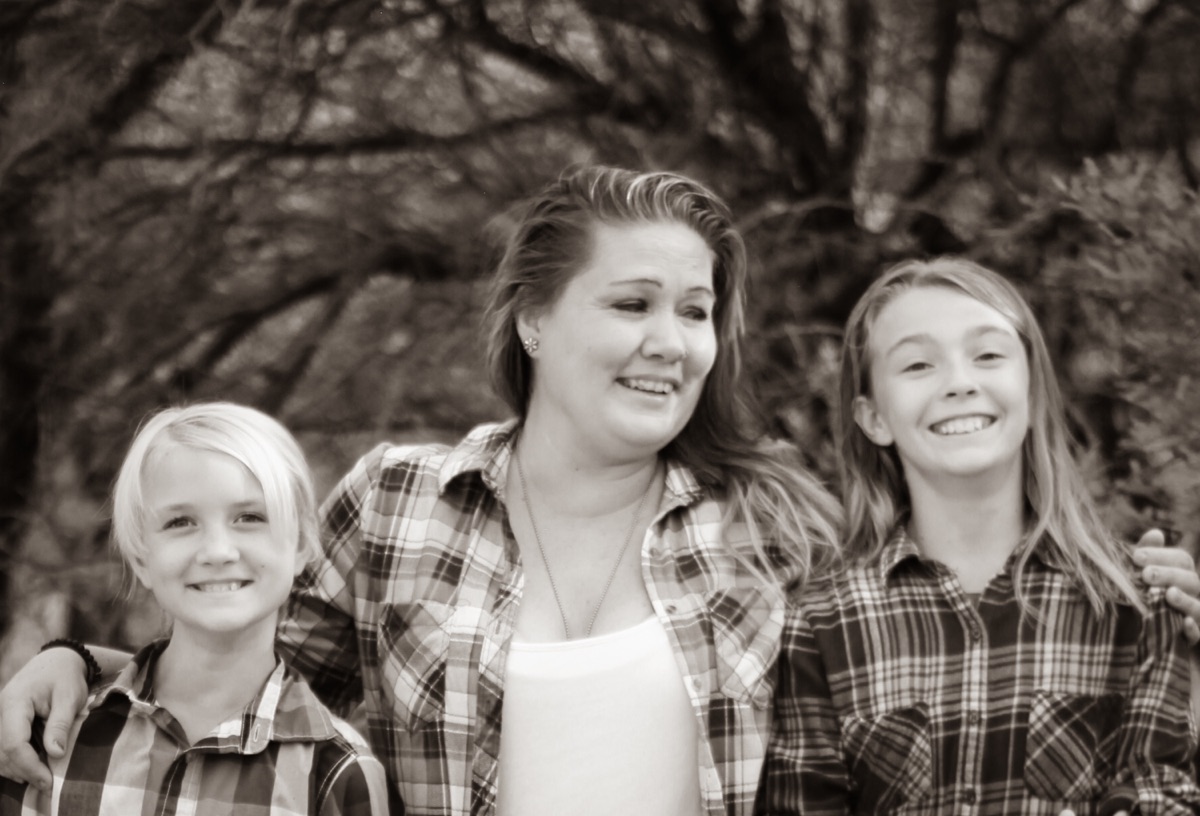 Mother with her daughters beneath a tree, photographed in black and white