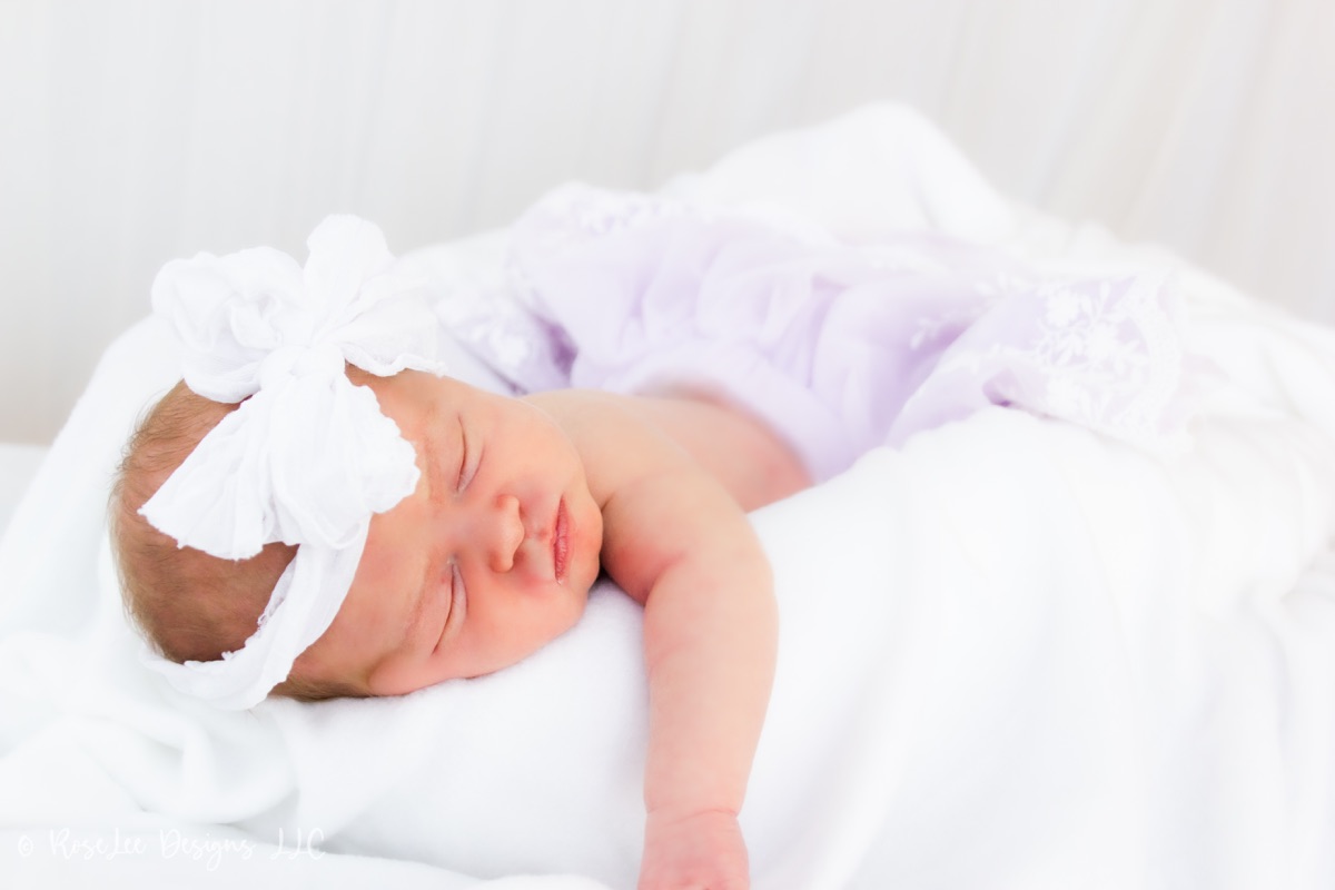 Close-up of a sleeping newborn with a soft white bow