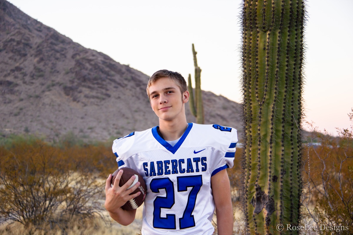 Football player holding a ball beside a saguaro cactus