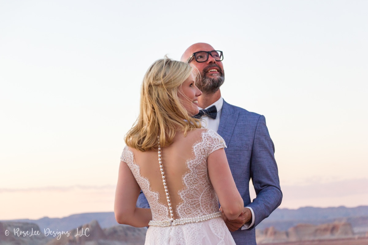 Bride and groom laughing together beside a desert lake