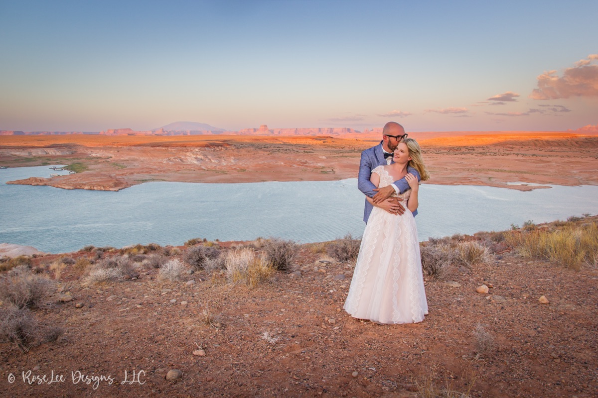 Newlyweds overlooking a wide desert lake at sunset