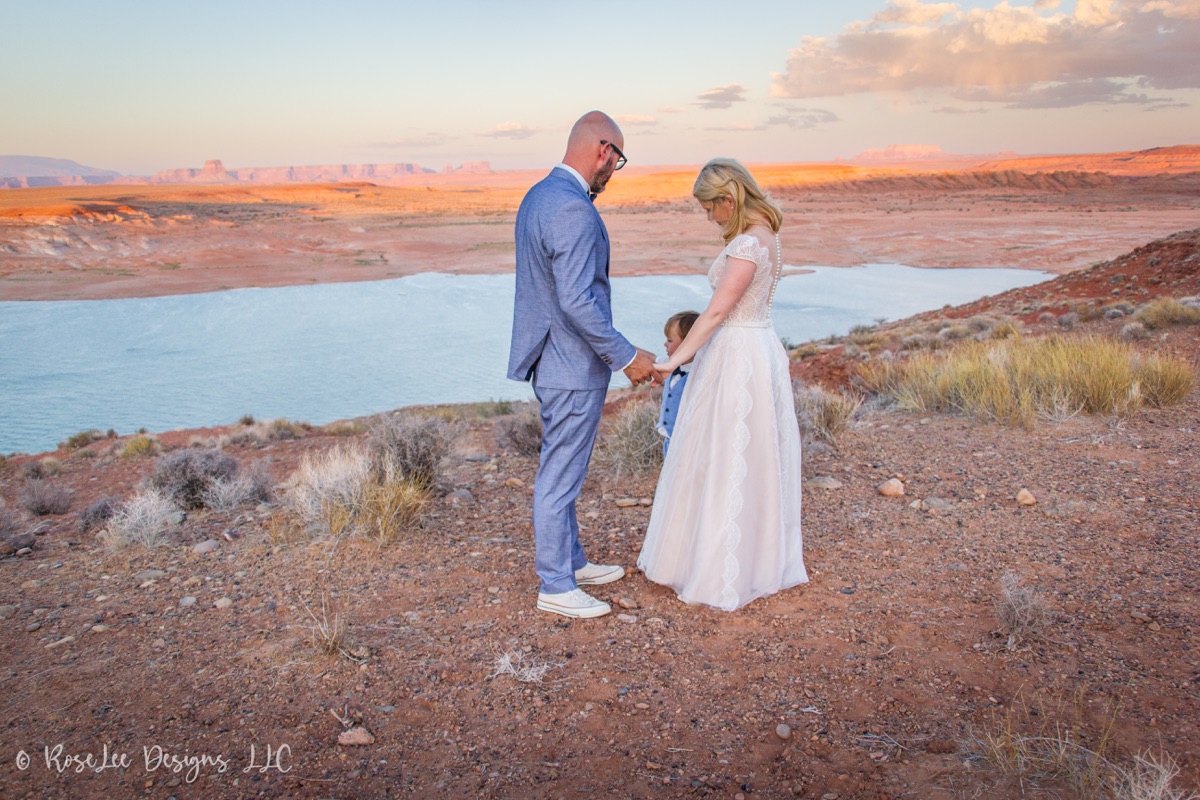 Bride and groom facing one another beside the lake
