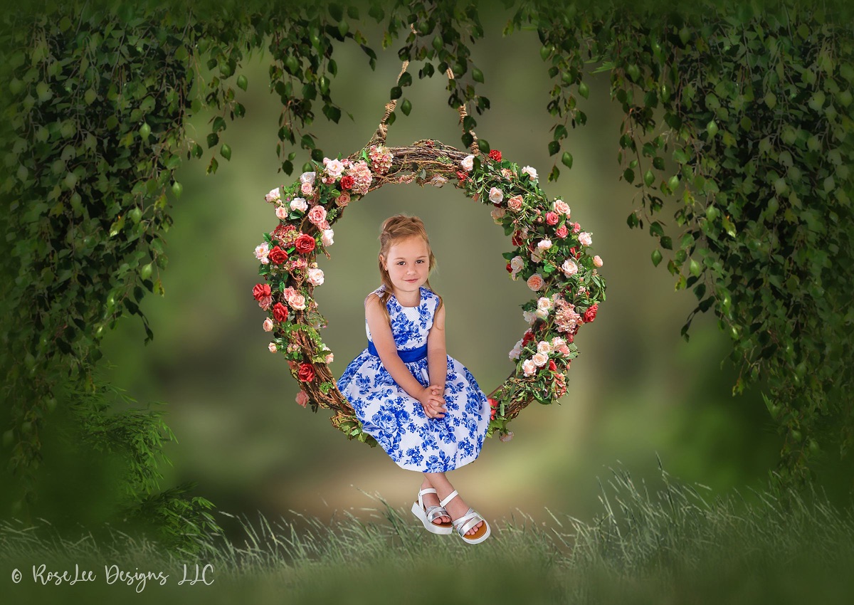 Creative portrait of a young girl seated inside a floral wreath in a woodland scene