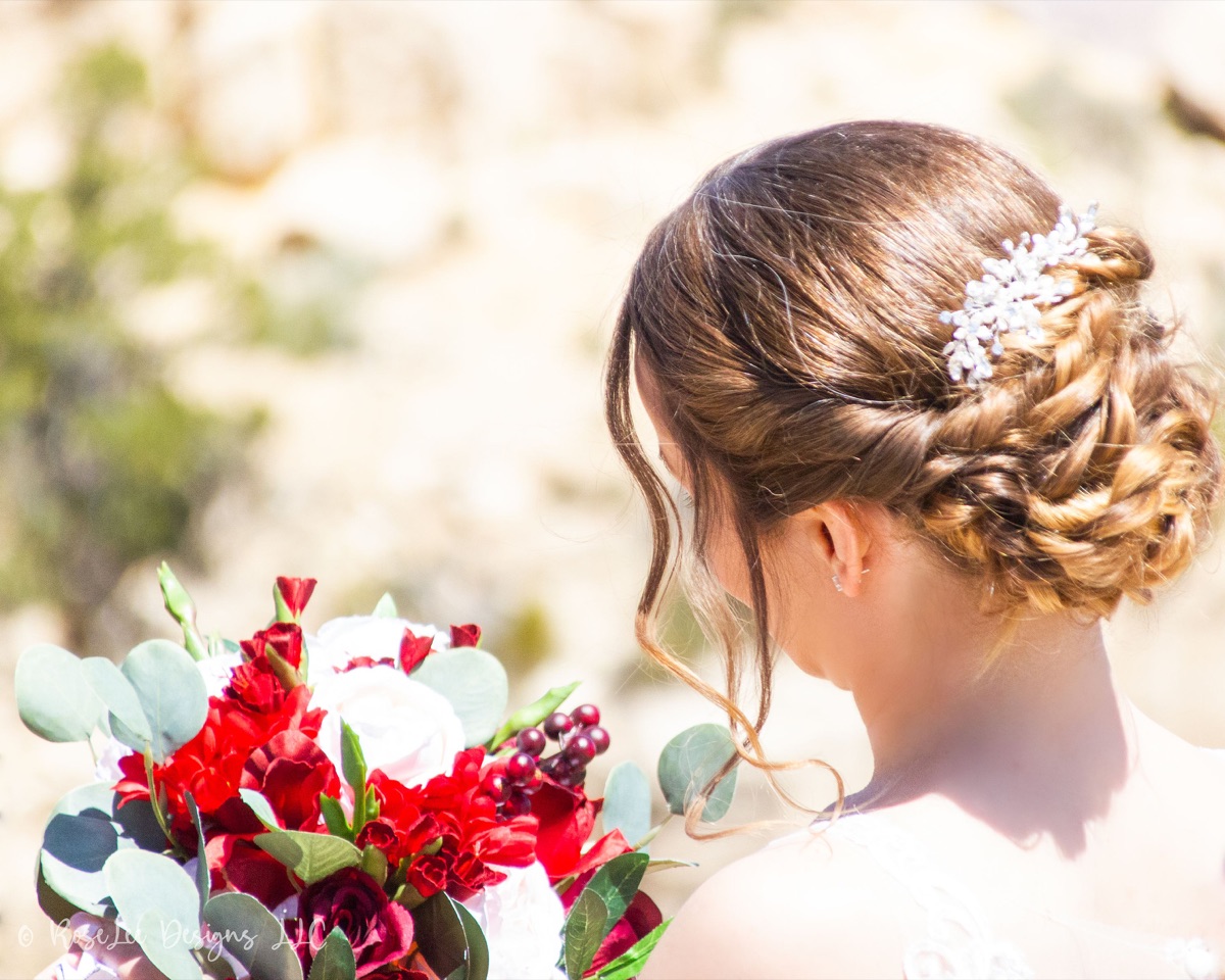 Detail of a bride’s braided hair and red rose bouquet