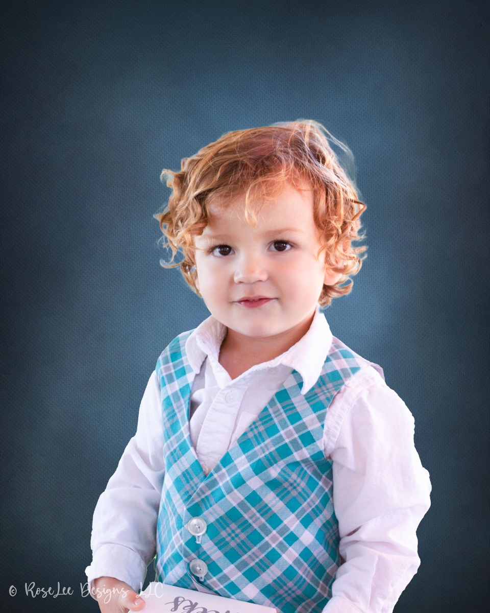 Young boy wearing a vest and bow tie in a studio portrait
