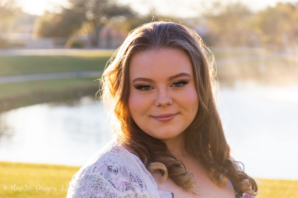 Young woman in lace with golden backlight beside the water