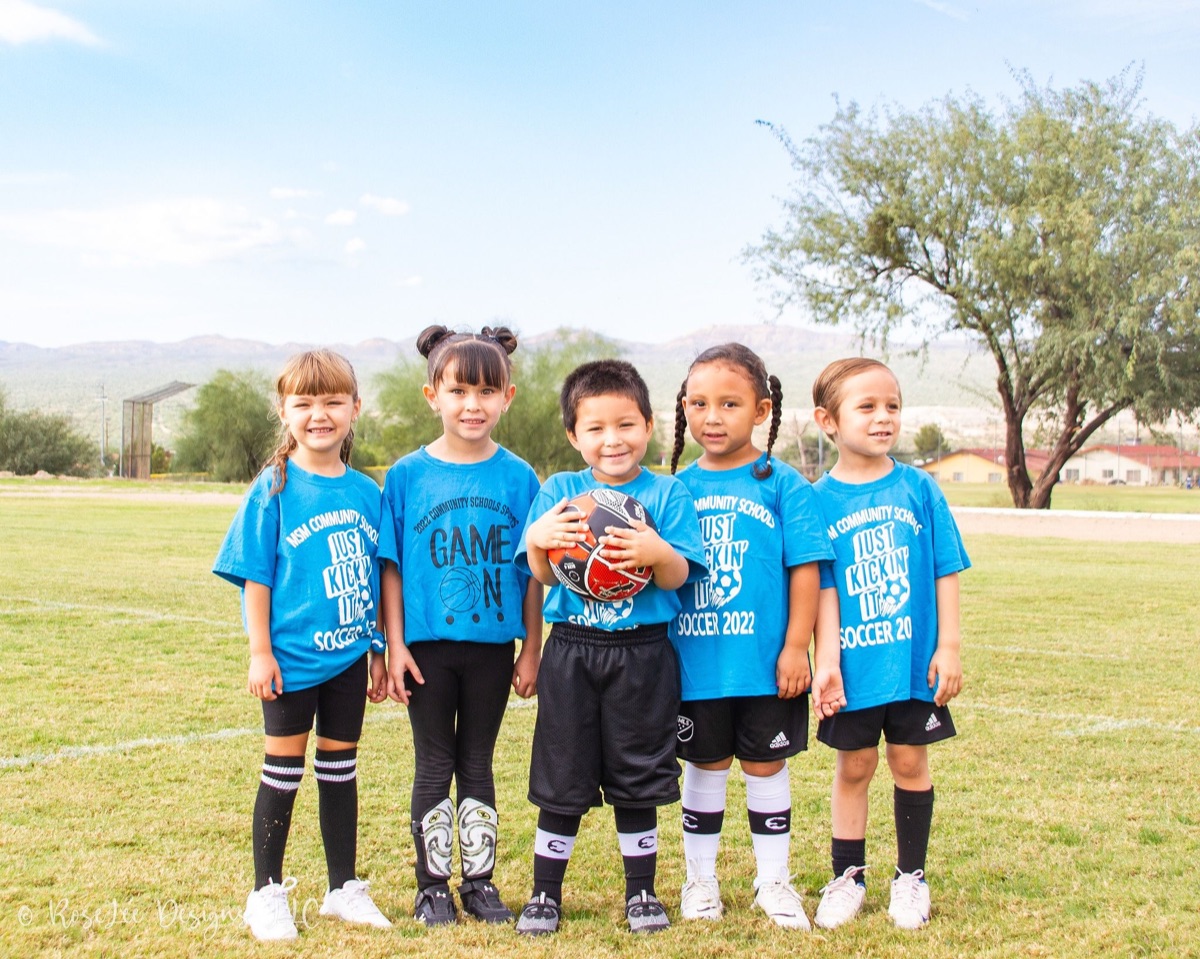 Young soccer teammates standing shoulder to shoulder on the field